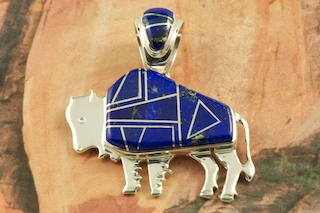 Stunning Buffalo Pendant featuring Genuine Blue Lapis inlaid between ribbons of Sterling Silver. Free 18" Sterling Silver Chain with Purchase of Pendant. Sterling Silver Pendant Designed by Navajo Artist Calvin Begay. Signed by the artist.