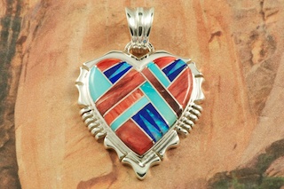 Beautiful Heart Pendant featuring Genuine Sleeping Beauty Turquoise, Spiny Oyster Shell and Blue Lapis inlaid between ribbons of Sterling Silver. Pretty Fire and Ice Lab Opal Accents. Free 18" Sterling Silver Chain with Purchase of Pendant. Created by Navajo Artist Rick Tolino. Signed by the artist.